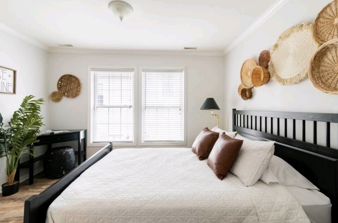 Bright bedroom with woven basket wall decor and black bed frame