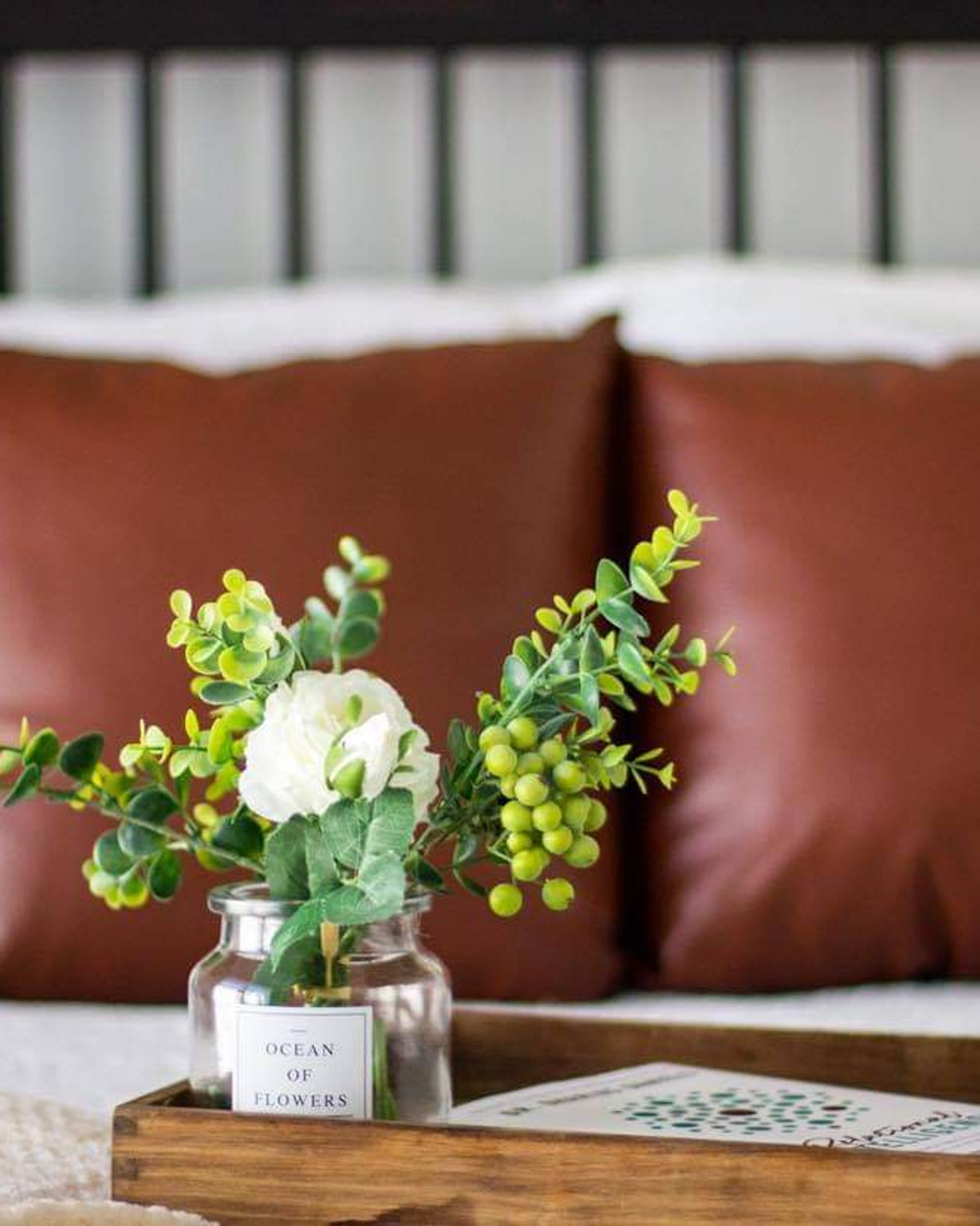 Styled bedroom with rust-toned pillows and fresh greenery